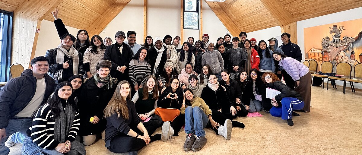 Große Gruppe von internationalen Freiwilligen in einem dreieckigen Saal