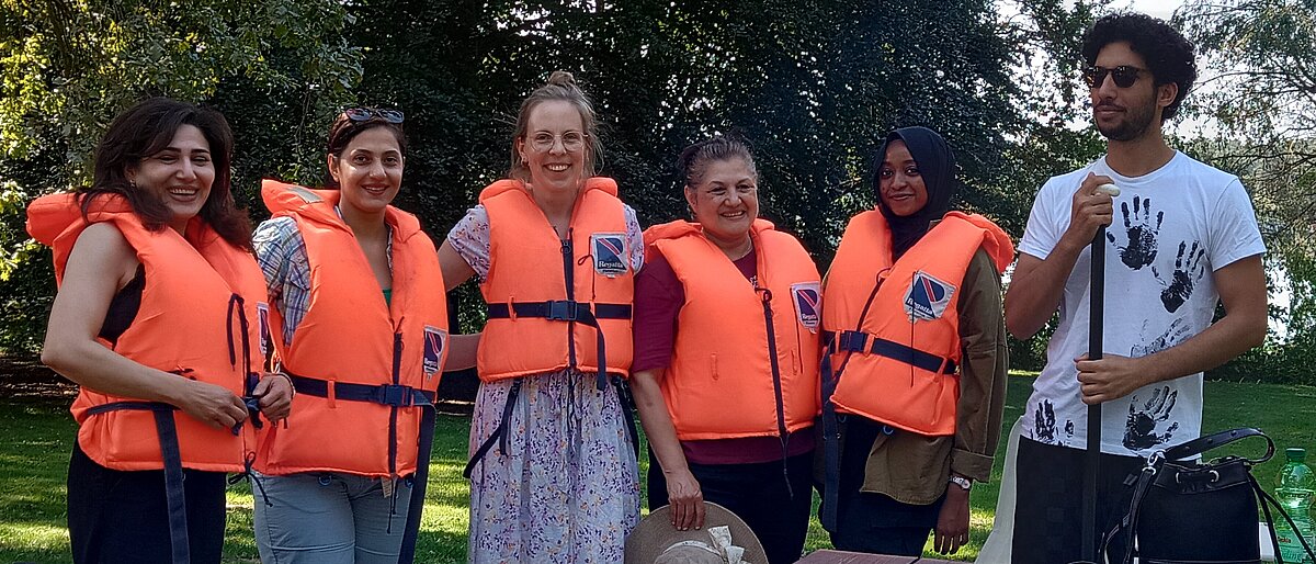 Gruppe internationaler Freiwilliger mit orangenen Schwimmwesten