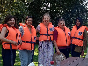 Gruppe internationaler Freiwilliger mit orangenen Schwimmwesten