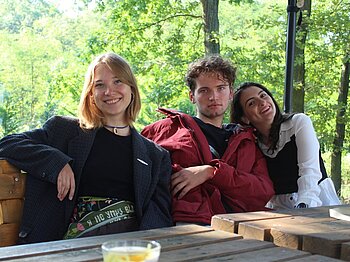 Drei junge Menschen sitzen an einem Tisch im Wald